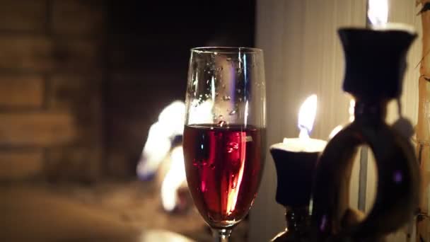 Christmas, New year. A glass of drink sits on the mantelpiece next to burning candles . - Felvétel, videó