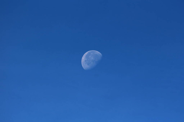 Imagem claramente visível da fase Waning gibbous Lua no céu azul claro fundo tomado no início da manhã do dia quente de outono
 - Foto, Imagem
