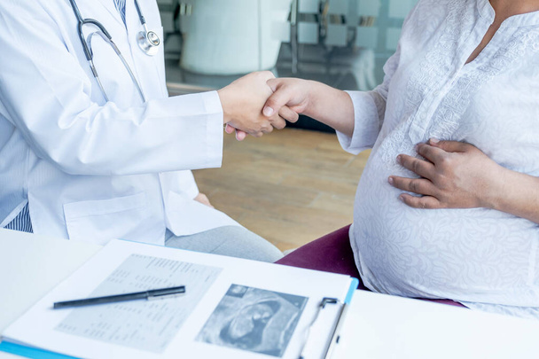 De arts schud de hand na controle van de gezondheid en adviseren zwangerschap aan zwangere vrouwen. - Foto, afbeelding