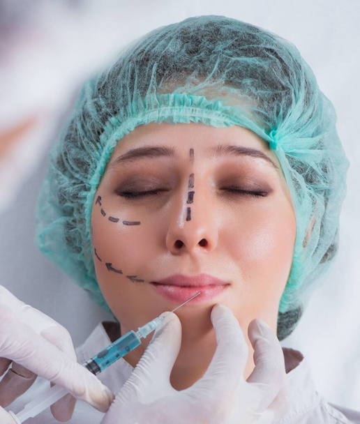 Пластический хирург готовится к операции на женском лице - Фото, изображение