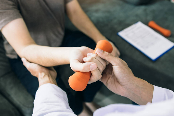 Ázsiai fizioterapeuták segítenek felemelni a betegek karját, hogy súlyzókat neveljenek a klinikán végzett rehabilitációján keresztül.. - Fotó, kép