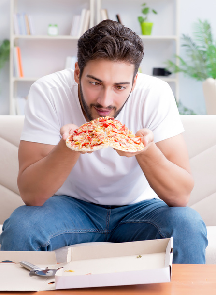 Az ember pizzát eszik, otthon eszik, pihentető pihen. - Fotó, kép