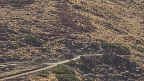 Lone nomad rides on a horse at country road over broad sunny mountain slope - Footage, Video
