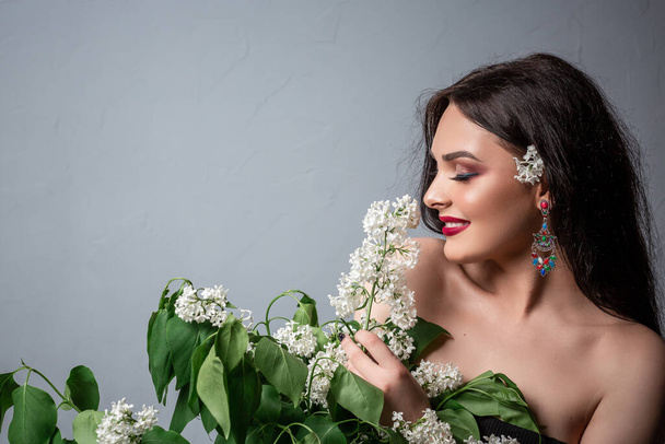 Girl enjoy life without allergy. Sniffing flowers. Pretty brunette girl enjoying floral aroma. Pollen allergy concept. Allergy remedy. Studio photo. - Photo, Image