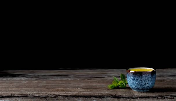 Bowl with matcha green tea on a vintage wooden table, dark background. Tea leaves next to the cup. Close-up, tea ceremony, minimalism, copy space. - Photo, Image