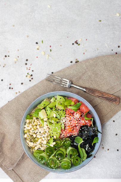 Salted salmon poke bowl with avocado, sea cale, cucumber, sesame seeds and bean sprouts - Photo, image