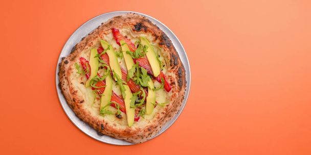 Close-up of a delicious smoked salmon pizza with cheese, avocado and smoked salmon. Sea-food. Orange background. - Foto, imagen