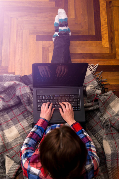 Egy nő dolgozik egy laptopon, miközben a padlón ül, felülnézetből. A távmunka fogalma. Szabadúszó. Otthon dolgozom. Keményen dolgozik. - Fotó, kép