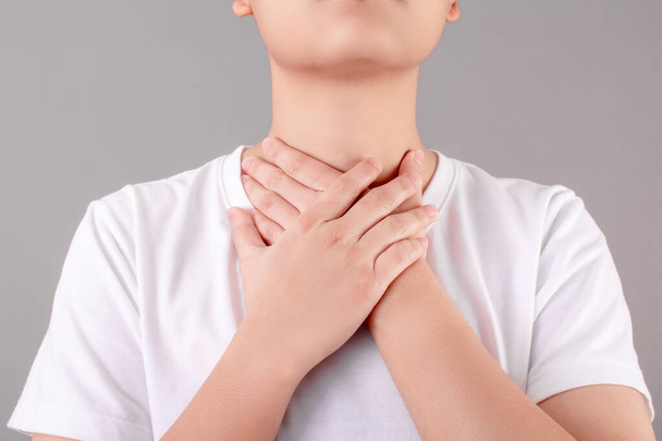 Aziatische mensen hebben keelpijn en raken hun nek aan met hun handen. Gezondheidszorg en medische concepten. - Foto, afbeelding