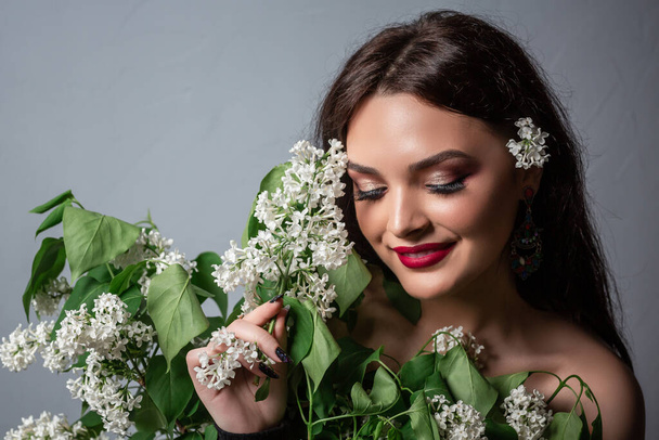 It is spring time. Natural cosmetics for skin. Pretty brunette girl in spring flower bloom. happy girl in lilac flower. blossom smell, allergy. Studio. - Photo, Image