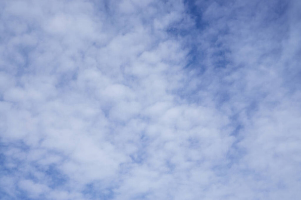 Ylöspäin, pehmeiden ja valkoisten pörröisten pilvien aalto syvän sinisen taivaan alla
 - Valokuva, kuva