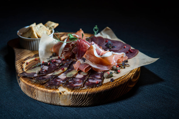 Sliced smoked sausage and jamon meat on a cutting board - 写真・画像