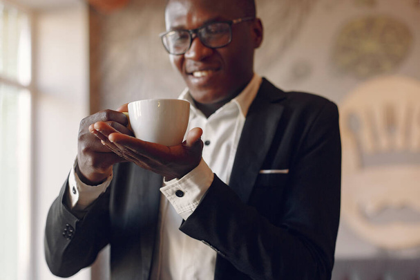 Black man standing in a cafe and drinking a coffee - Φωτογραφία, εικόνα
