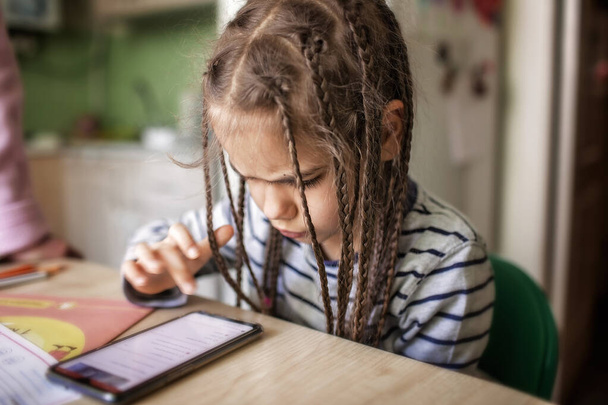 Nogal stijlvol schoolmeisje dat wiskunde studeert tijdens haar online les thuis, sociale afstand tijdens quarantaine, zelf-isolatie, online onderwijs concept - Foto, afbeelding