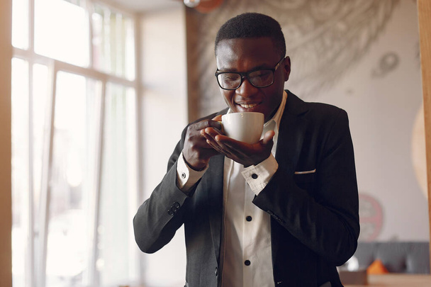 Black man standing in a cafe and drinking a coffee - Foto, imagen