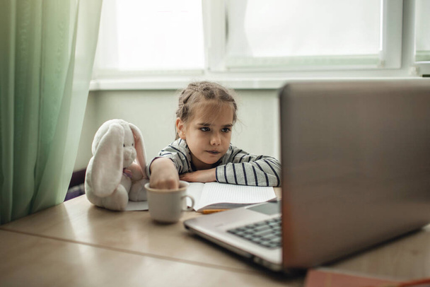 Elég stílusos iskolás lány tanul házi feladat közben ő online lecke otthon, társadalmi távolság karantén alatt, ön-elszigetelés, online oktatási koncepció - Fotó, kép