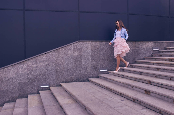 beautiful, young girl in a pink skirt and heels running down the stairs - Foto, imagen