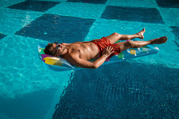 юноши в красном плавают коротко плавая в бассейне, мужчины в плавать коротко в бассейне во время отпуска, мужчины среднего возраста нормальный здоровый парень загар
 - Фото, изображение
