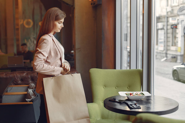 Stylish girls in a standing in a cafe with shopping bags - Фото, изображение