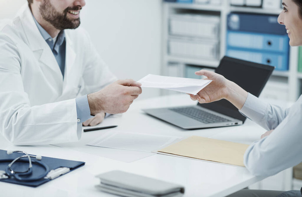 Doctor sitting at office desk and giving a prescription to a female patient, healthcare and medical treatment concept - Foto, Imagem