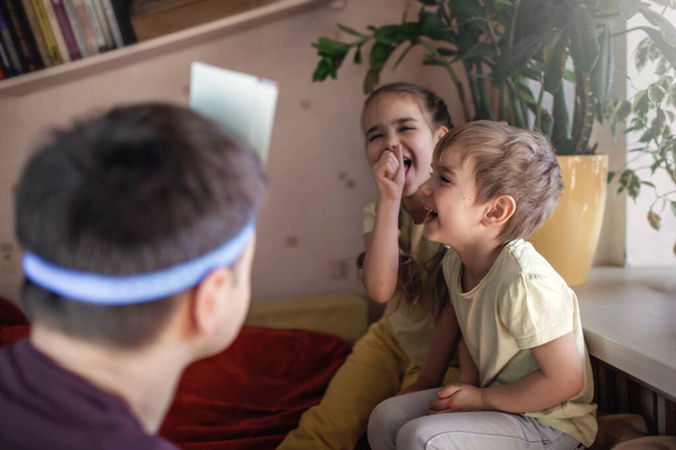 Šťastný dospělý otec hrát na palubě hry se svými dvěma dětmi v domácím interiéru, rodinné hodnoty vlastně, zůstat doma, život během karantény - Fotografie, Obrázek