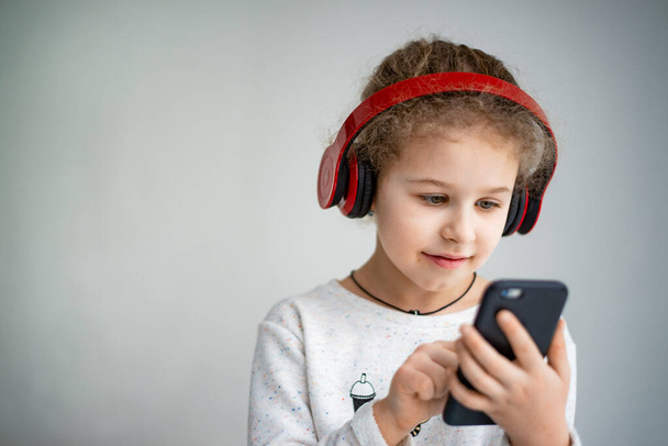 little girl in red headphones with a phone - Fotó, kép
