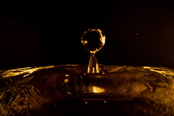 Πιτσιλιές νερού, χρυσές πιτσιλιές νερού απομονωμένες σε μαύρο φόντο, νερό - Φωτογραφία, εικόνα