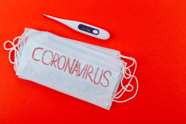 Protective medical mask with the inscription coronavirus on a red background. - Foto, afbeelding