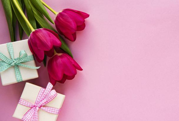 Beautiful tulips bouquet and gift boxes on a pink  pastel  background - Photo, Image