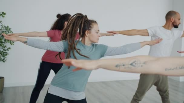Slow motion of group of young people training with instructor in yoga studio - Felvétel, videó