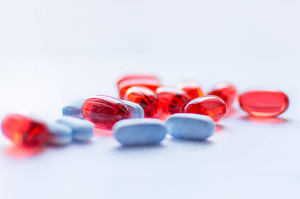 Rode en blauwe capsules op witte achtergrond. Farmaceutisch concept. Traditionele geneeskundige behandeling. - Foto, afbeelding