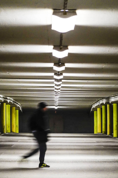 Tukholma, Ruotsi Mies kävelee parkkihallissa yöllä ilman autoja
. - Valokuva, kuva