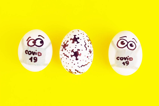 Eeaster symbol eggs in medical masks and painted coronavirus bacteria on yellow background, space for text, horizontal view. Easter quarantine concept for Easter holiday due to coronavirus epidemic. - 写真・画像