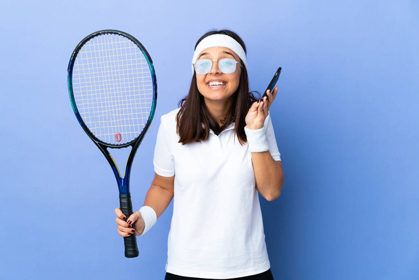 Fiatal nő teniszező elszigetelt háttér miközben egy beszélgetést a mobiltelefon valakivel - Fotó, kép