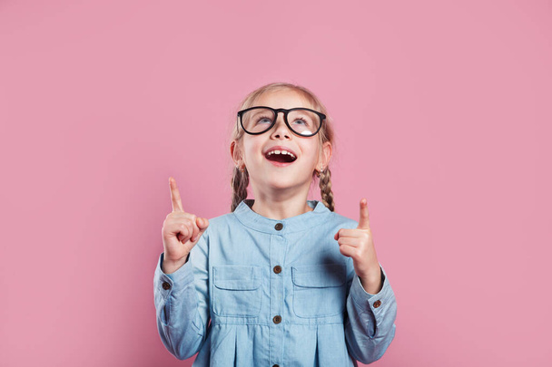 Clever little girl pointing up on pink background - Fotografie, Obrázek