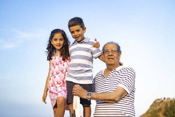 Grandfather and grandchildren against blue sky. Summer time. - Photo, Image