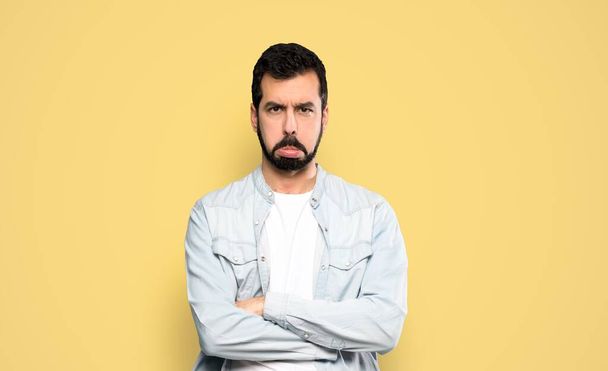 Handsome man with beard with sad and depressed expression over isolated yellow background - Photo, Image