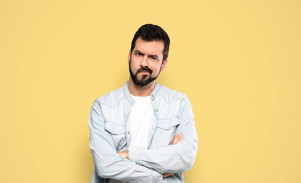 Handsome man with beard feeling upset over isolated yellow background - Photo, Image
