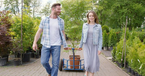 Щаслива молода пара в квітковому магазині щойно купила гарне горщикове дерево
 - Фото, зображення