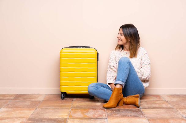 Traveler woman with suitcase sitting on the floor looking to the side - Photo, Image