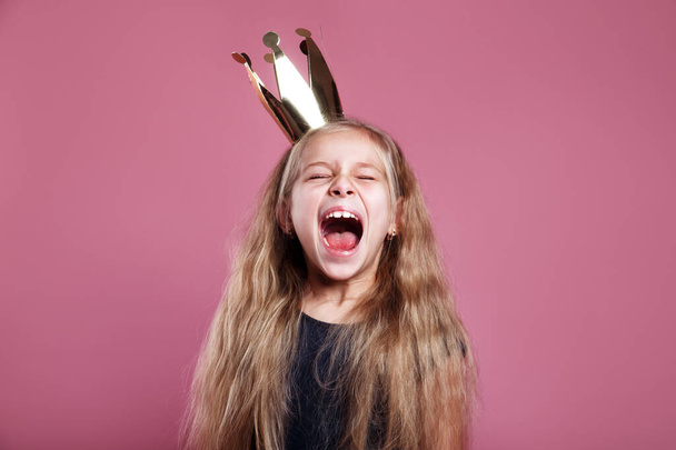 Shouting little girl in crown on pink background - Fotó, kép