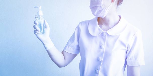 Femme tient une bouteille de gel d'alcool dans sa main pour nettoyer fréquemment les mains et prévenir l'infection par le coronavirus, auto-soin initial lors d'une crise épidémique. Concept d'autoprévention et de soins de santé
. - Photo, image