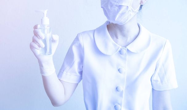 Woman holds a bottle of alcohol gel in her hand for frequently cleaning hands and prevent coronavirus infection, initial self-care during an epidemic crisis. Self-prevention and healthcare concept. - Photo, image