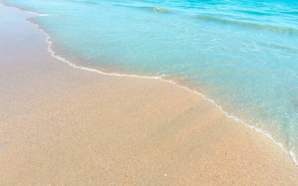 Praia de areia marrom e pequena onda de água azul no mar
 - Foto, Imagem