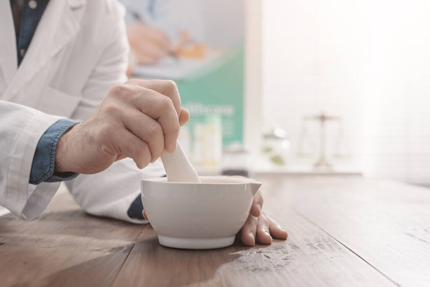 Professional pharmacist grinding a medical preparation using a mortar and pestle, pharmacy and medicine concept, hands close up - Photo, image