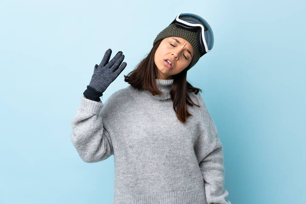 Snowboard gözlüklü karışık kayakçı kız izole edilmiş mavi arka planda yorgun ve hasta bir ifadeyle.. - Fotoğraf, Görsel