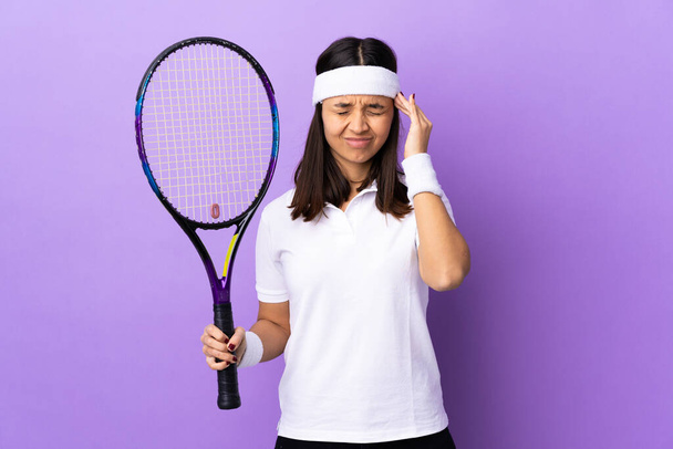 Jonge vrouw tennisspeler over geïsoleerde achtergrond met hoofdpijn - Foto, afbeelding