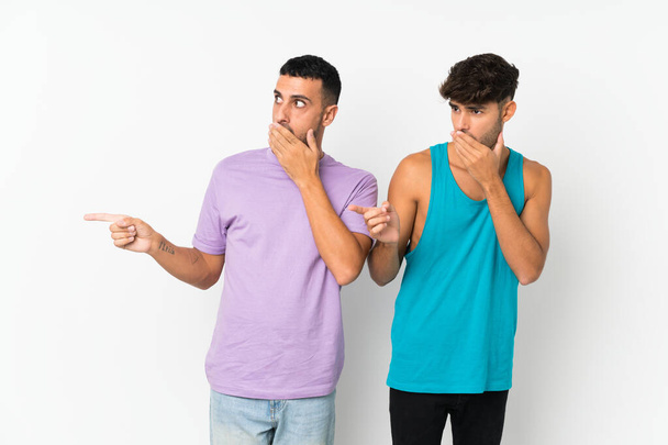 Two men over isolated background pointing finger to the side with a surprised face - Photo, Image