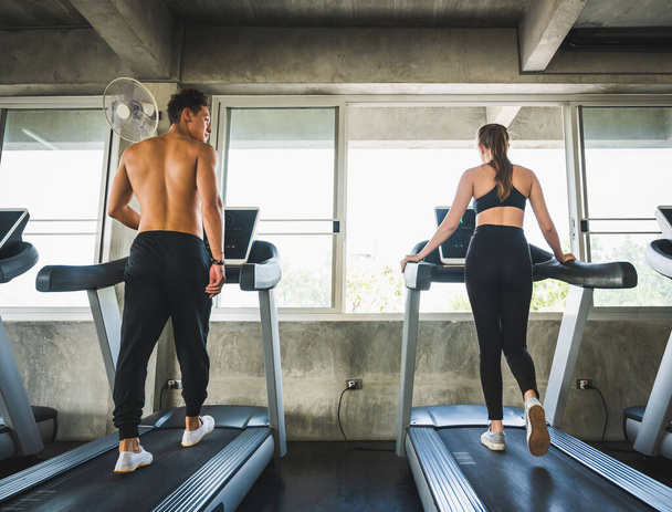 Mężczyzna i kobieta Ćwiczą bieganie na bieżni, by zawsze zachować zdrowie. - Zdjęcie, obraz