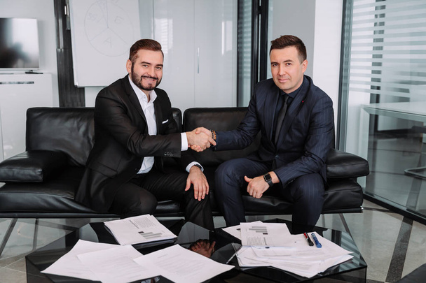 Two satisfied businessmen shake hands after successful negotiations - Foto, afbeelding